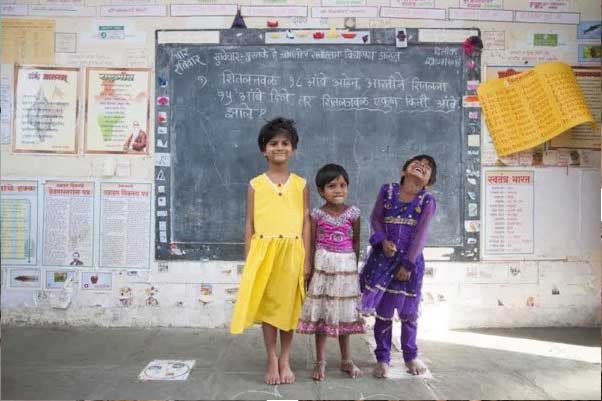 Girls smiling in a classroom supported by community education work